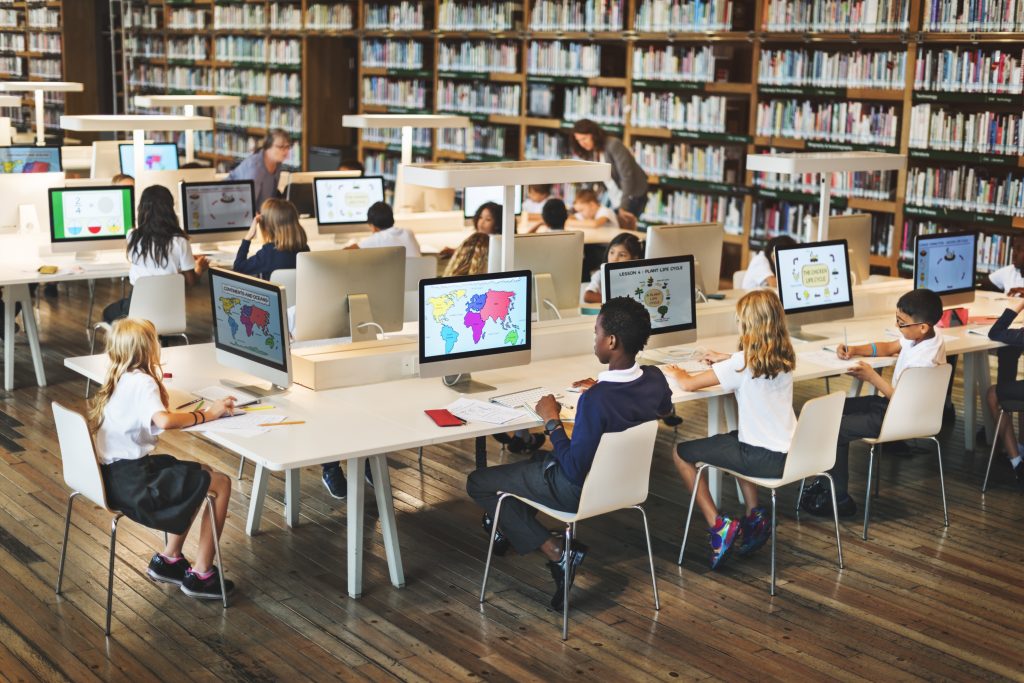 Photo of young pupils using compluters in a library