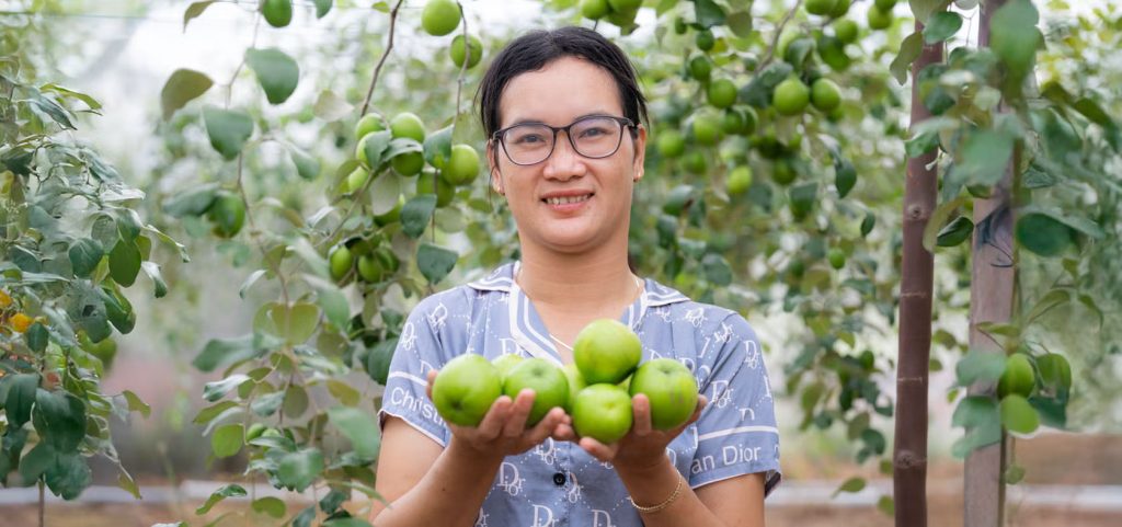 Photo of a female beneficiary in Ninh Thuan (Viet Nam), holding well-nourished apples from her farm