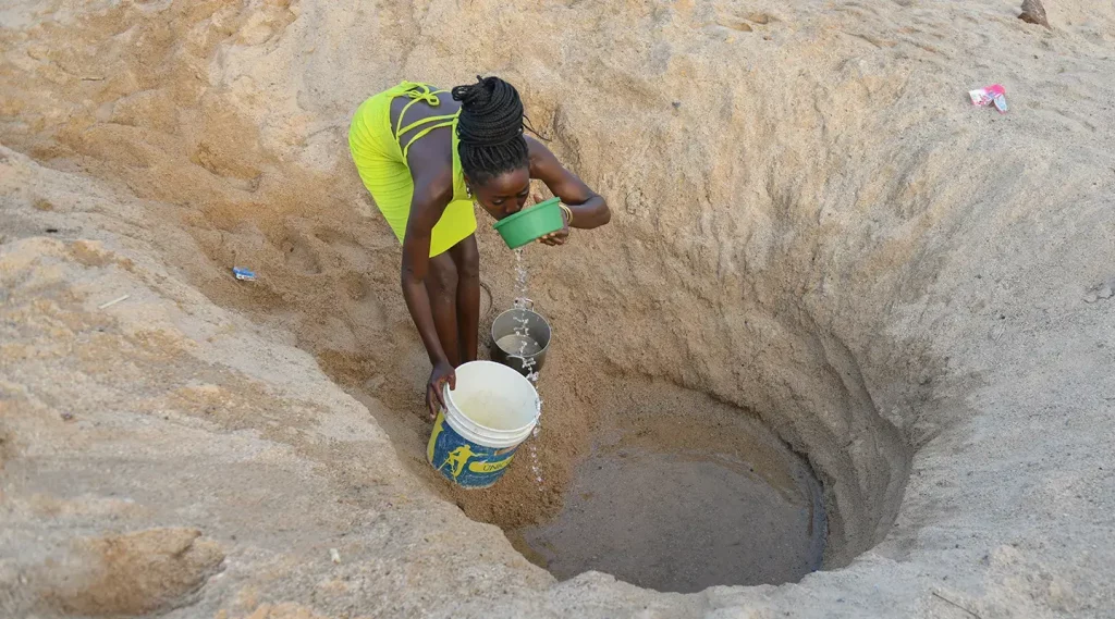 woman collection and drinking water from a ground water source.